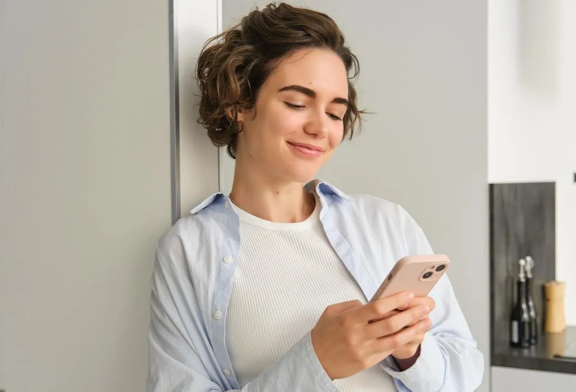 Portrait of brunette woman with smartphone sending message checking her mobile application ordering